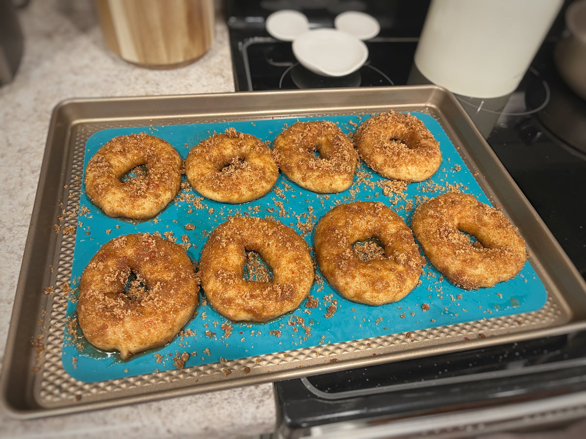 Eight flat, spread-out sugar topped bagels on a sheet pan.