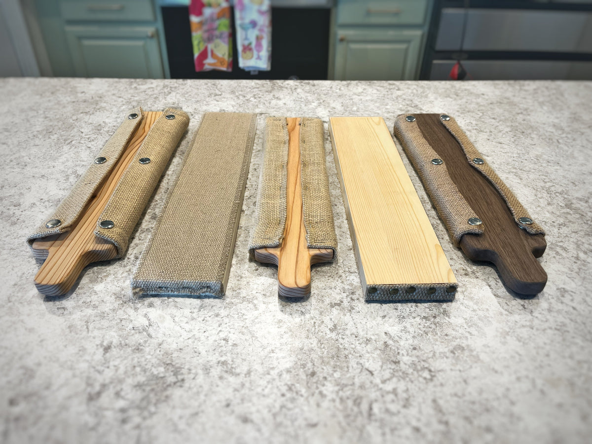 Classic and Signature bagel boards beside two traditional cedar rectangle boards and two walnut boards on a workbench.