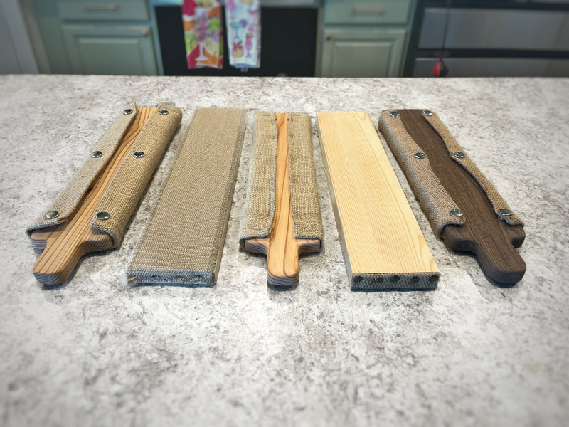 Classic and Signature bagel boards beside two traditional cedar rectangle boards and two walnut boards on a workbench.