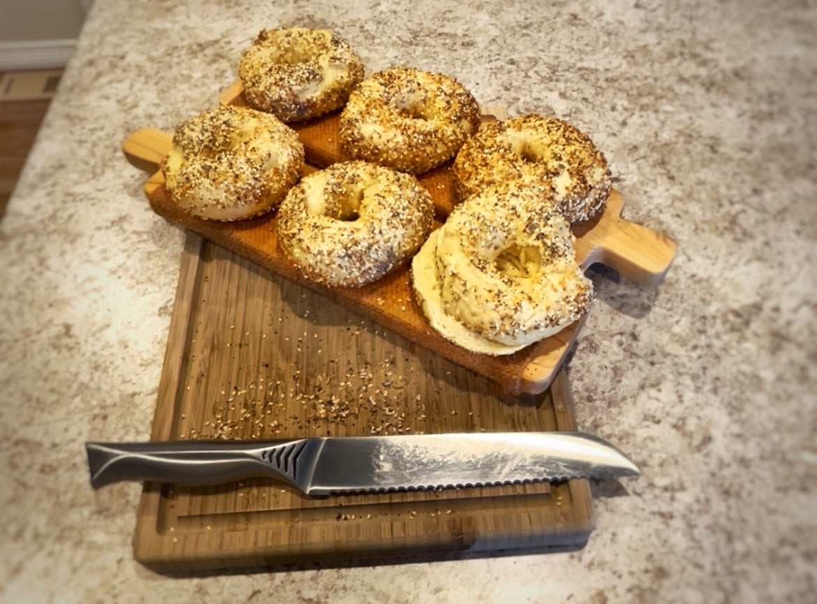 Everything bagels sliced and display on cutting board.