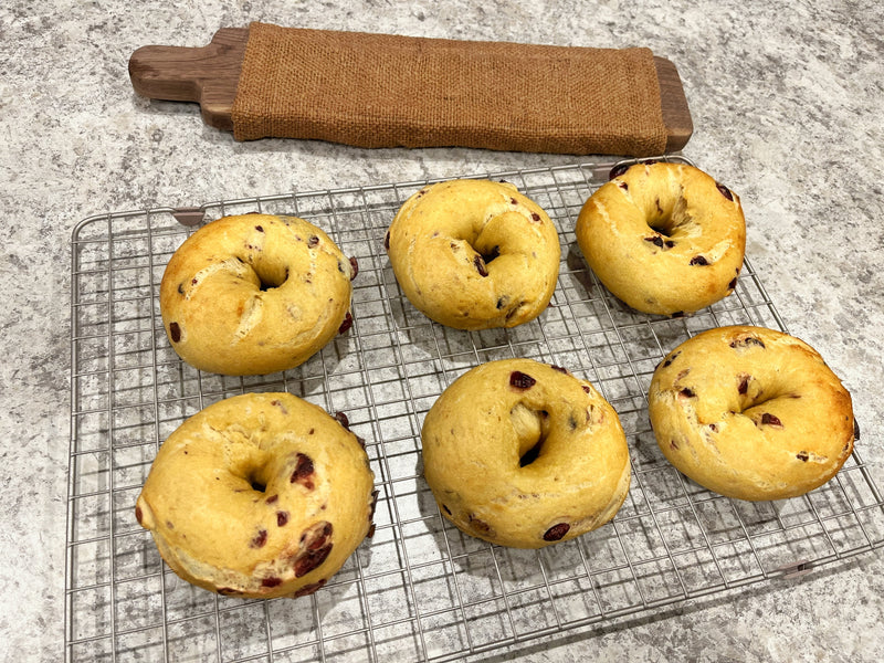 6 orange cranberry holiday bagels cooling on rack.