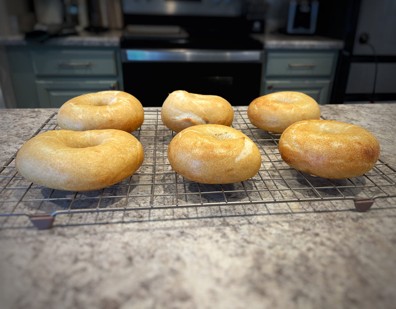 6 bagels cooling on a rack, all formed using different shaping methods.