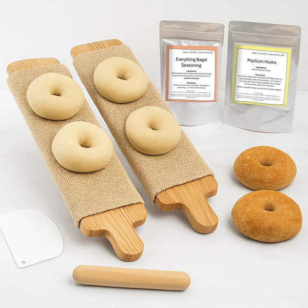 Cedar bagel boards arranged with gluten-free bagel mix, brown sugar boil additive, everything seasoning, and tools on a white countertop.